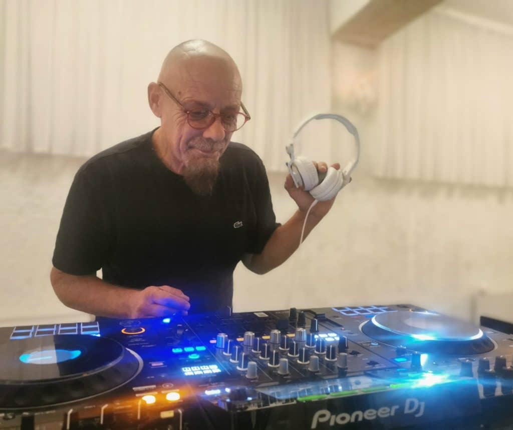 dj fredy za pioneer mixetom drži slušalice u lijevoj ruci